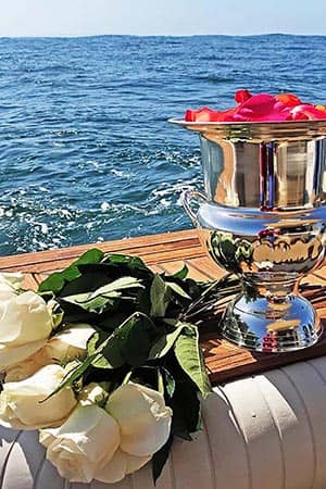Urn at back of yacht with flowers for ash scattering